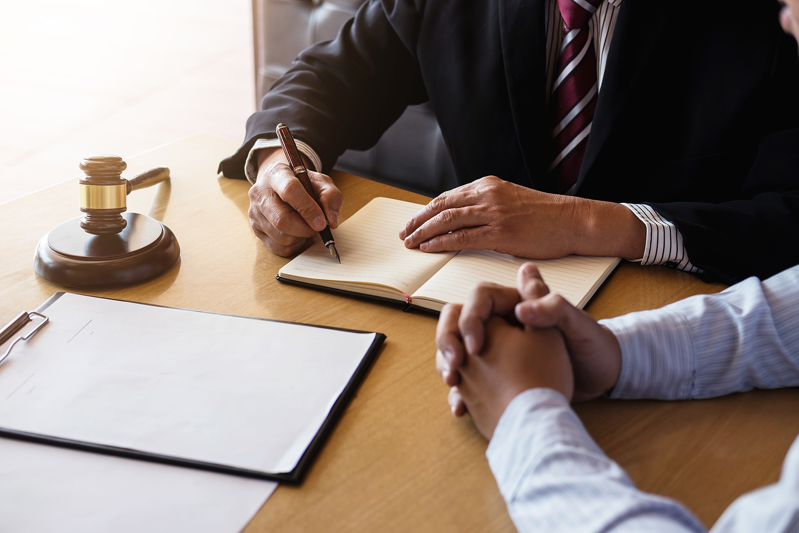 Lawyer discussing a legal case with a client at a desk, with a judge’s gavel and legal documents nearby.