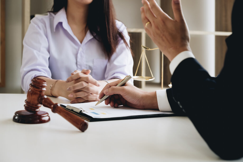 Criminal defense lawyer discussing a case with a client at a desk, with a gavel and scales of justice in the background.